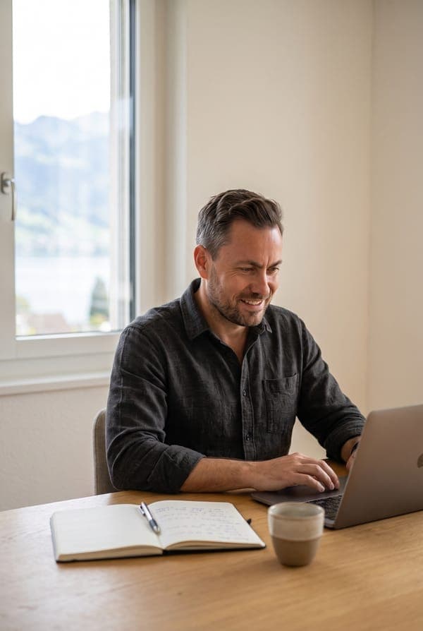 Javier Pérez working at his desk, with a lake and mountains through the window